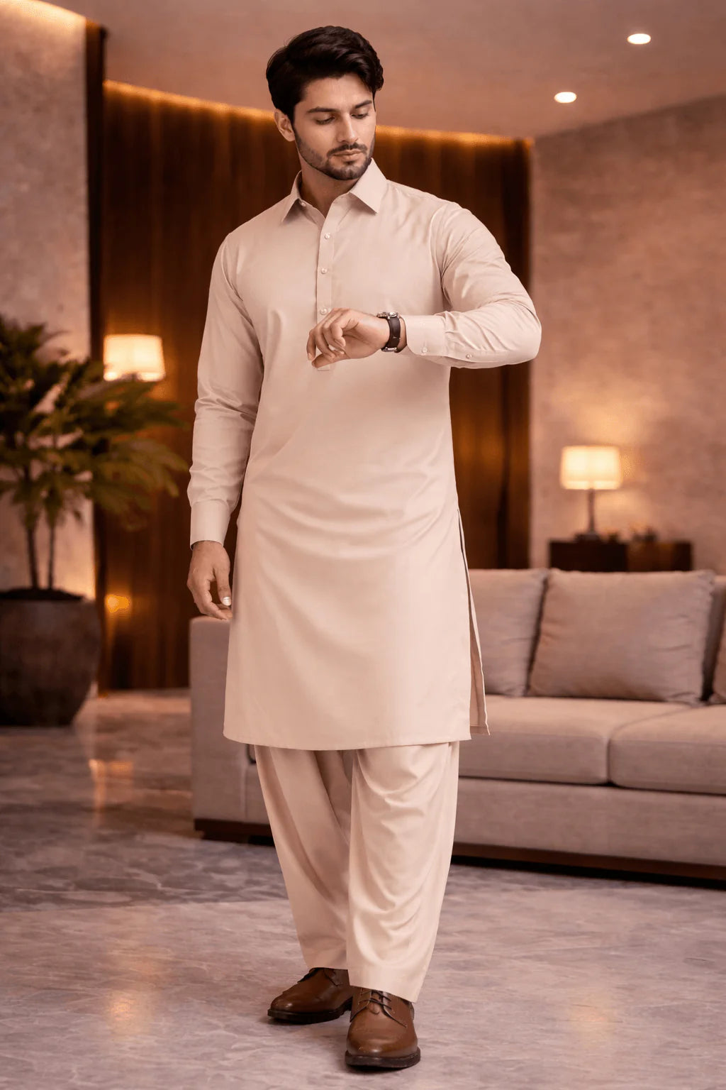 Man in a beige kurta and pants standing in a well-lit room.