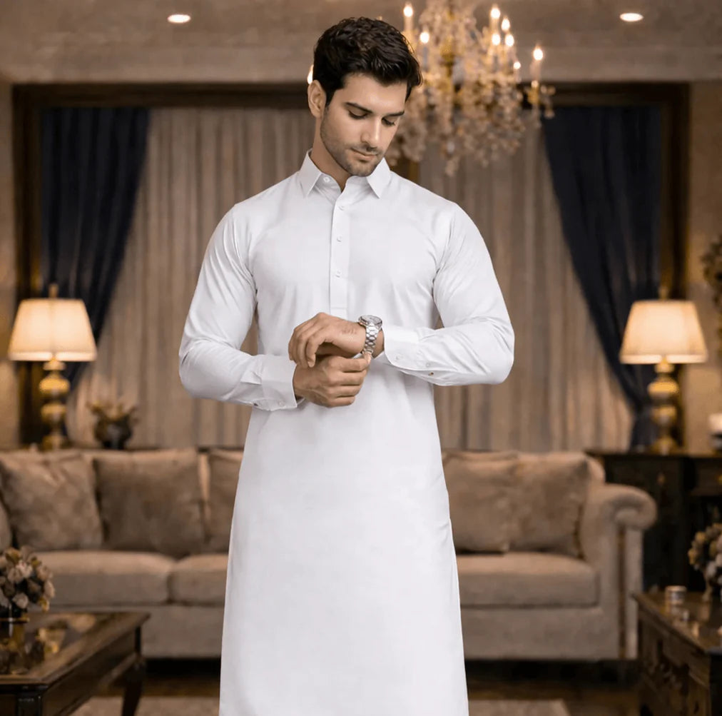 Man in a white traditional outfit standing in a living room.